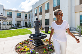 A woman wearing white pants and sunglasses is walking past a fountain. AI generated content