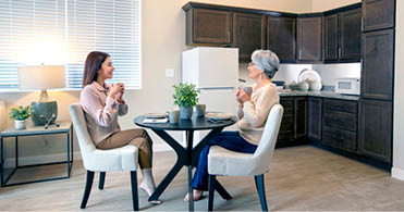Two women sitting at a table. Description generated by AI